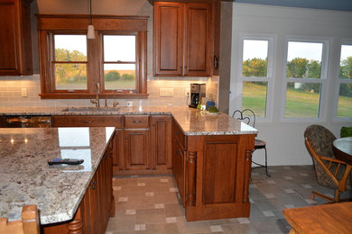 ウィチタにあるおしゃれなアイランドキッチン (グレーのキッチンパネル、シルバーの調理設備、御影石カウンター、セラミックタイルのキッチンパネル、磁器タイルの床) の写真