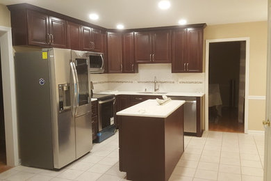 Example of a small minimalist l-shaped beige floor eat-in kitchen design in Philadelphia with a double-bowl sink, raised-panel cabinets, dark wood cabinets, stainless steel appliances, an island and white countertops