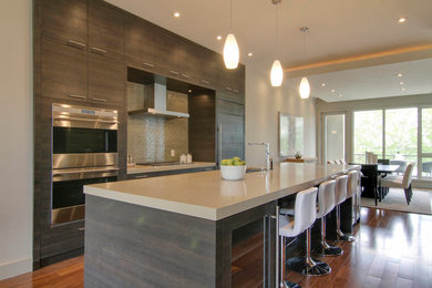 Inspiration for a large timeless galley medium tone wood floor eat-in kitchen remodel in Calgary with an undermount sink, flat-panel cabinets, gray cabinets, quartz countertops, gray backsplash, glass tile backsplash, stainless steel appliances and an island