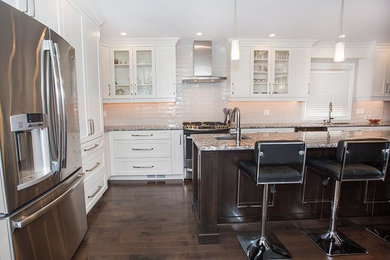 Enclosed kitchen - large contemporary l-shaped dark wood floor enclosed kitchen idea in Toronto with an undermount sink, shaker cabinets, white cabinets, granite countertops, white backsplash, subway tile backsplash, stainless steel appliances and an island