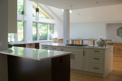 Example of a mid-sized minimalist light wood floor eat-in kitchen design in Vancouver with an undermount sink, shaker cabinets, white cabinets, stainless steel appliances and an island