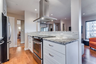 Inspiration for a mid-sized modern galley medium tone wood floor eat-in kitchen remodel in Vancouver with a single-bowl sink, recessed-panel cabinets, white cabinets, granite countertops, gray backsplash, stone slab backsplash and stainless steel appliances