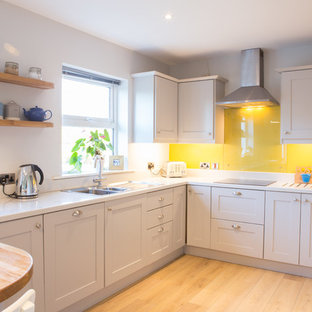 Contemporary kitchen in Dublin with yellow splashback and glass sheet splashback.