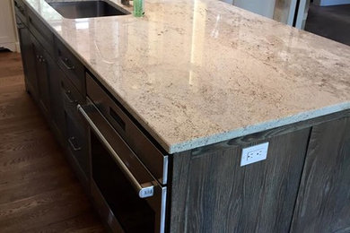 Example of a kitchen design in Austin with an undermount sink, medium tone wood cabinets, granite countertops and an island