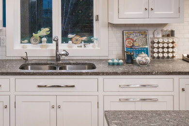 Medium sized contemporary kitchen in Portland Maine with a double-bowl sink, beaded cabinets, white cabinets, granite worktops, white splashback, metro tiled splashback, stainless steel appliances and an island.