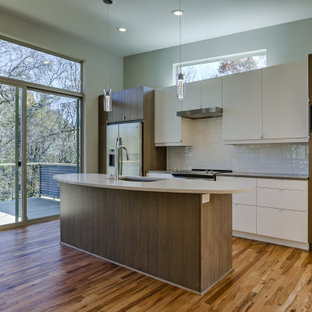 Mid-sized mid-century modern open concept kitchen inspiration - Open concept kitchen - mid-sized 1960s single-wall medium tone wood floor and brown floor open concept kitchen idea in Kansas City with an undermount sink, flat-panel cabinets, medium tone wood cabinets, quartzite countertops, white backsplash, ceramic backsplash, stainless steel appliances, an island and white countertops