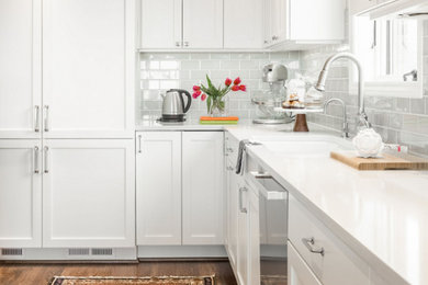 Moderne Küche mit Schrankfronten mit vertiefter Füllung, weißen Schränken, Küchenrückwand in Grau, Rückwand aus Metrofliesen, Küchengeräten aus Edelstahl, Quarzit-Arbeitsplatte, braunem Holzboden und braunem Boden in Seattle