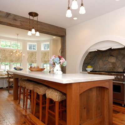 Eat-in kitchen - large rustic l-shaped medium tone wood floor eat-in kitchen idea in New York with stainless steel appliances, recessed-panel cabinets, white cabinets, a drop-in sink, gray backsplash and an island
