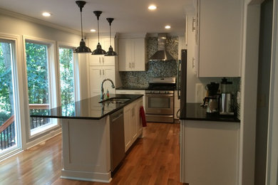 Transitional l-shaped light wood floor kitchen photo in Raleigh with a double-bowl sink, shaker cabinets, white cabinets, granite countertops, multicolored backsplash, mosaic tile backsplash, stainless steel appliances and an island