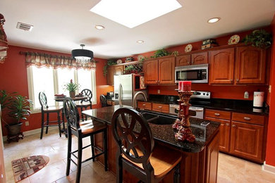 Elegant ceramic tile kitchen photo in Atlanta with an undermount sink, raised-panel cabinets, medium tone wood cabinets, granite countertops, stainless steel appliances and an island