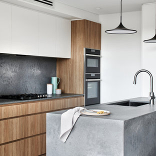 Mid-sized scandinavian single-wall eat-in kitchen in Sydney with an undermount sink, flat-panel cabinets, medium wood cabinets, quartz benchtops, grey splashback, black appliances, dark hardwood floors, with island, brown floor and grey benchtop.