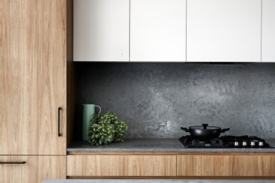 Inspiration för ett mellanstort skandinaviskt grå linjärt grått kök och matrum, med en undermonterad diskho, släta luckor, skåp i mellenmörkt trä, bänkskiva i kvarts, grått stänkskydd, svarta vitvaror, mörkt trägolv, en köksö och brunt golv