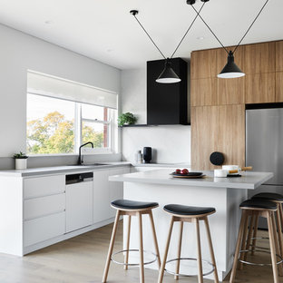 This is an example of a mid-sized contemporary l-shaped kitchen in Sydney with a double-bowl sink, flat-panel cabinets, medium wood cabinets, white splashback, stainless steel appliances, medium hardwood floors, with island, brown floor and grey benchtop.