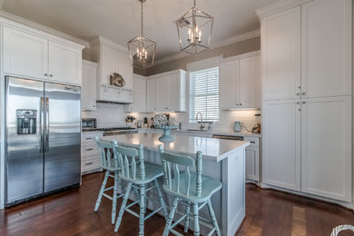 Eat-in kitchen - mid-sized coastal l-shaped medium tone wood floor and brown floor eat-in kitchen idea in Houston with an undermount sink, shaker cabinets, white cabinets, quartz countertops, white backsplash, subway tile backsplash, stainless steel appliances and an island