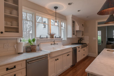 Kitchen - mid-sized transitional medium tone wood floor kitchen idea in Other with a farmhouse sink, recessed-panel cabinets, white cabinets, marble countertops, white backsplash, subway tile backsplash, stainless steel appliances and an island