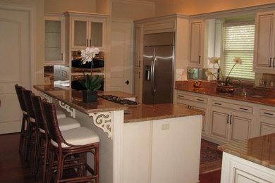 Mid-sized transitional l-shaped dark wood floor and brown floor open concept kitchen photo in New Orleans with beaded inset cabinets, white cabinets, granite countertops, beige backsplash, stainless steel appliances and an island