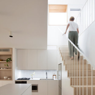 Design ideas for a beach style l-shaped kitchen in Sydney with an undermount sink, flat-panel cabinets, white cabinets, window splashback, stainless steel appliances, light hardwood floors, with island, beige floor and grey benchtop.