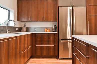 This is an example of a large modern l-shaped enclosed kitchen in Chicago with a submerged sink, flat-panel cabinets, dark wood cabinets, engineered stone countertops, stainless steel appliances, light hardwood flooring, an island, brown floors, grey splashback, cement tile splashback and white worktops.