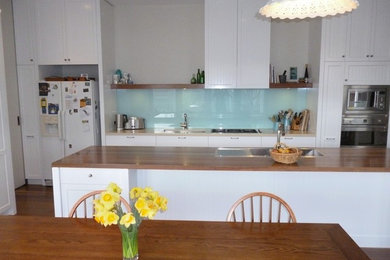 Пример оригинального дизайна: кухня в современном стиле с белой техникой без острова