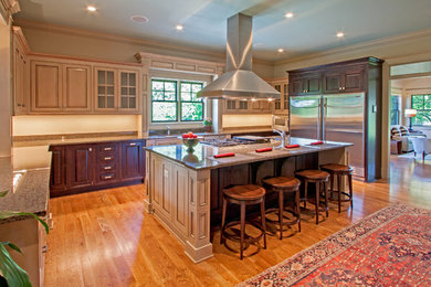 Bild på ett avskilt, stort vintage u-kök, med en undermonterad diskho, luckor med upphöjd panel, beige skåp, granitbänkskiva, beige stänkskydd, rostfria vitvaror, mellanmörkt trägolv och en köksö