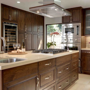 Foto di una grande cucina minimal con ante con bugna sagomata, paraspruzzi con piastrelle a mosaico, elettrodomestici in acciaio inossidabile, ante in legno bruno, lavello sottopiano, isola, top in quarzo composito, paraspruzzi multicolore e pavimento in pietra calcarea