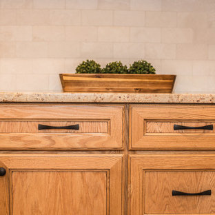 Photo of a mid-sized traditional galley open plan kitchen in Other with a farmhouse sink, shaker cabinets, medium wood cabinets, granite benchtops, beige splashback, ceramic splashback, stainless steel appliances, vinyl floors, a peninsula and brown floor.