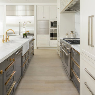 Large contemporary single-wall open plan kitchen in Salt Lake City with an undermount sink, recessed-panel cabinets, white cabinets, marble benchtops, white splashback, stone slab splashback, stainless steel appliances, light hardwood floors, multiple islands and beige floor.