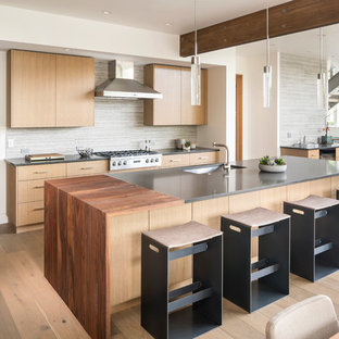Modelo de cocina comedor rústica, grande, con fregadero bajoencimera, armarios con paneles lisos, puertas de armario de madera clara, encimera de cuarcita, salpicadero verde, salpicadero de azulejos de piedra, electrodomésticos de acero inoxidable, una isla, encimeras grises, suelo de madera clara y suelo beige