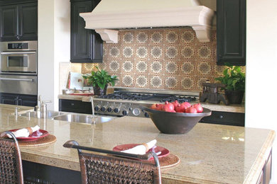 Inspiration for a contemporary kitchen remodel in Orlando with a double-bowl sink, recessed-panel cabinets, black cabinets, granite countertops, cement tile backsplash and an island