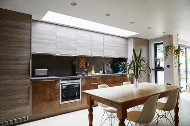 Imagen de cocina lineal actual abierta sin isla con fregadero integrado, armarios con paneles lisos, electrodomésticos con paneles y encimera de acrílico
