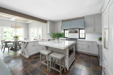 Inspiration for a transitional slate floor and brown floor eat-in kitchen remodel in Chicago with a farmhouse sink, shaker cabinets, gray cabinets, quartz countertops, white backsplash, subway tile backsplash, stainless steel appliances, an island and white countertops