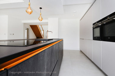 Photo of a large modern kitchen/diner in Essex with an integrated sink, flat-panel cabinets, grey cabinets, composite countertops, stainless steel appliances, marble flooring, an island and black worktops.