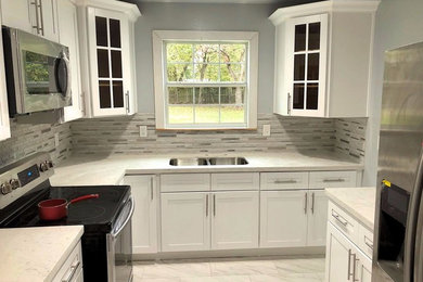Example of a small transitional u-shaped gray floor enclosed kitchen design in Houston with an undermount sink, shaker cabinets, white cabinets, quartzite countertops, gray backsplash, stone tile backsplash, stainless steel appliances and no island