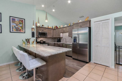 マイアミにある中くらいなトランジショナルスタイルのおしゃれなキッチン (珪岩カウンター、シルバーの調理設備、茶色いキッチンカウンター) の写真