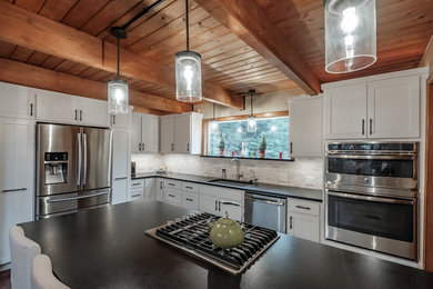 Large farmhouse l-shaped dark wood floor and brown floor eat-in kitchen photo in Portland with a single-bowl sink, shaker cabinets, white cabinets, granite countertops, white backsplash, stone tile backsplash, stainless steel appliances, an island and black countertops