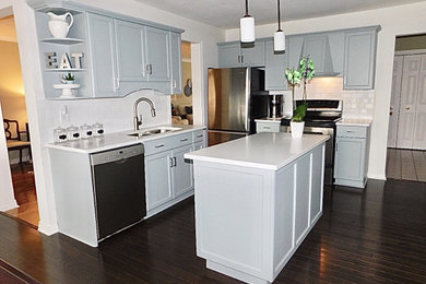 Example of a mid-sized cottage u-shaped dark wood floor and brown floor enclosed kitchen design in Toronto with a farmhouse sink, shaker cabinets, blue cabinets, quartzite countertops, subway tile backsplash, stainless steel appliances, an island and white countertops
