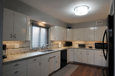 Example of a mid-sized trendy u-shaped eat-in kitchen design in Milwaukee with a double-bowl sink, white cabinets, granite countertops, gray backsplash, glass tile backsplash, black appliances and no island