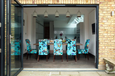 ロンドンにある高級な広いコンテンポラリースタイルのおしゃれなキッチン (アンダーカウンターシンク、フラットパネル扉のキャビネット、グレーのキャビネット、クオーツストーンカウンター、青いキッチンパネル、ガラス板のキッチンパネル、シルバーの調理設備、磁器タイルの床) の写真