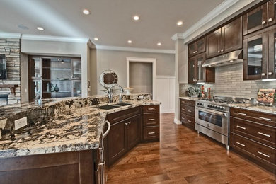 Example of a mid-sized classic laminate floor open concept kitchen design in San Francisco with a double-bowl sink, shaker cabinets, brown cabinets, granite countertops, multicolored backsplash, stone slab backsplash, stainless steel appliances and an island