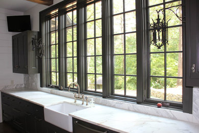 Example of a mid-sized classic l-shaped kitchen design in Birmingham with a farmhouse sink, beaded inset cabinets, black cabinets, marble countertops, stone slab backsplash and an island