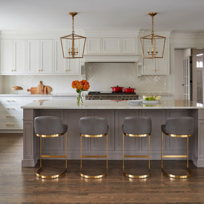 Large transitional l-shaped medium tone wood floor and brown floor kitchen photo in Chicago with white cabinets, marble countertops, white backsplash, ceramic backsplash, stainless steel appliances, an island, beige countertops and shaker cabinets
