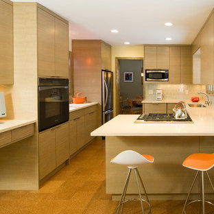 Imagen de cocina moderna con fregadero bajoencimera, armarios con paneles lisos, puertas de armario de madera clara, salpicadero blanco y electrodomésticos de acero inoxidable