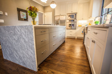 Inspiration for a mid-sized transitional u-shaped dark wood floor and brown floor eat-in kitchen remodel in Atlanta with a farmhouse sink, recessed-panel cabinets, white cabinets, marble countertops, gray backsplash, subway tile backsplash, stainless steel appliances, an island and white countertops