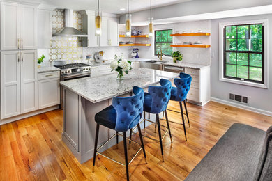 Example of a mid-sized trendy u-shaped medium tone wood floor and beige floor eat-in kitchen design in Atlanta with a farmhouse sink, shaker cabinets, white cabinets, granite countertops, white backsplash, porcelain backsplash, stainless steel appliances, an island and multicolored countertops