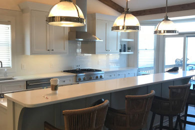 Large transitional l-shaped medium tone wood floor, brown floor and exposed beam eat-in kitchen photo in Other with an undermount sink, recessed-panel cabinets, gray cabinets, quartz countertops, white backsplash, subway tile backsplash, stainless steel appliances, an island and white countertops