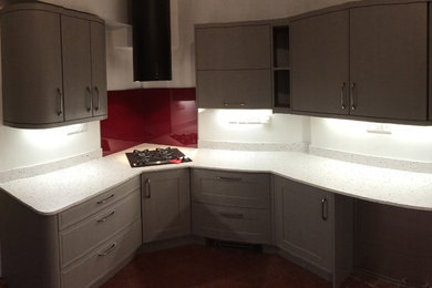 This is an example of a small contemporary galley enclosed kitchen in Other with a built-in sink, flat-panel cabinets, grey cabinets, quartz worktops, red splashback, integrated appliances and no island.