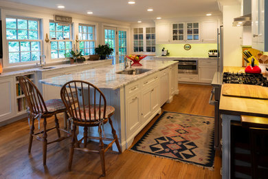Inspiration for a large timeless medium tone wood floor and brown floor eat-in kitchen remodel with an undermount sink, flat-panel cabinets, white cabinets, wood countertops, white backsplash, ceramic backsplash, stainless steel appliances, an island and brown countertops