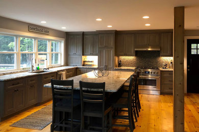 Kitchen - large transitional l-shaped medium tone wood floor and brown floor kitchen idea in Boston with an undermount sink, recessed-panel cabinets, gray cabinets, granite countertops, multicolored backsplash, mosaic tile backsplash, paneled appliances and an island