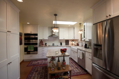 シアトルにあるおしゃれなキッチン (エプロンフロントシンク、シェーカースタイル扉のキャビネット、白いキャビネット、クオーツストーンカウンター、白いキッチンパネル、サブウェイタイルのキッチンパネル、シルバーの調理設備、無垢フローリング) の写真