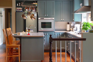 ニューヨークにあるトランジショナルスタイルのおしゃれなL型キッチン (シルバーの調理設備、青いキャビネット) の写真